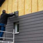 Ouvrier posant isolation jaune et bardage gris